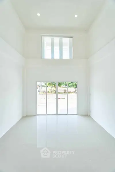 Spacious high-ceiling living room with large windows and abundant natural light.