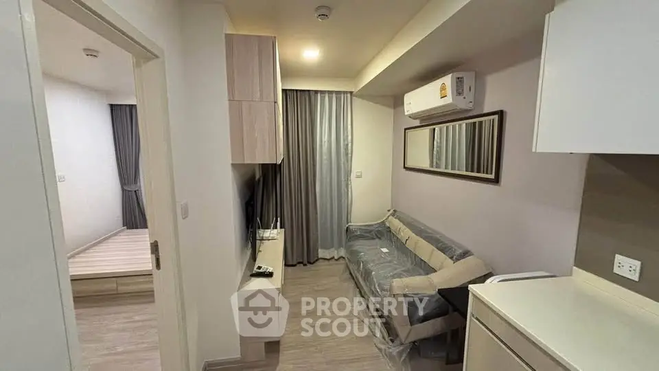 Modern apartment interior with cozy living room and bedroom, featuring sleek furniture and neutral tones.