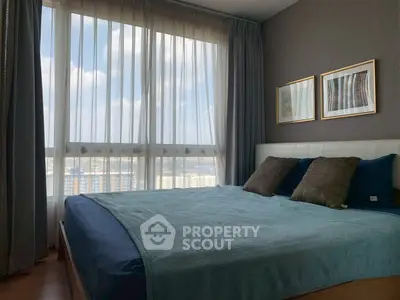Spacious bedroom with large windows offering a stunning city view, perfect for relaxation and comfort.