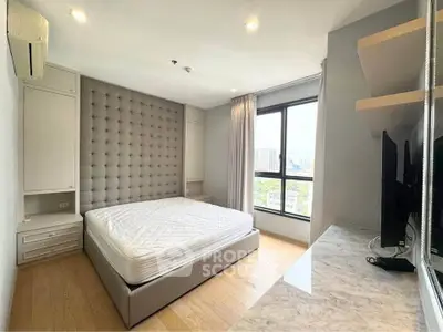 Spacious bedroom with modern decor and large window offering city views.
