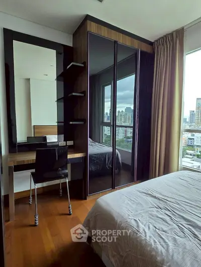 Modern bedroom with city view, featuring sleek furniture and large windows.