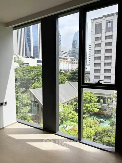 Stunning cityscape view from modern apartment with floor-to-ceiling windows and lush greenery.