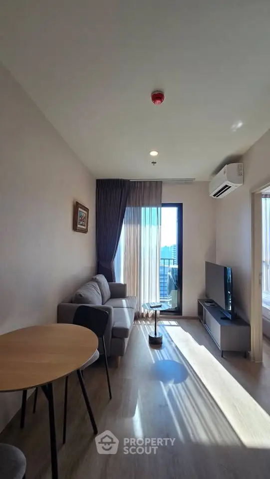Modern living room with natural light, featuring a cozy sofa, TV, and dining area in a stylish apartment.
