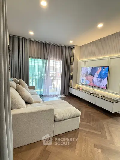 Modern living room with elegant decor and large sofa, featuring a stylish entertainment unit and floor-to-ceiling curtains.
