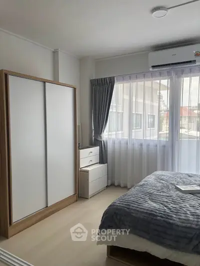 Bright and cozy bedroom with modern furnishings and large window for natural light.