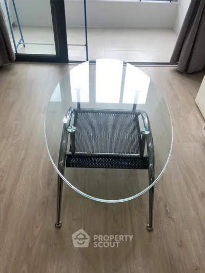 Modern glass coffee table in a stylish living room with wooden flooring and balcony view.