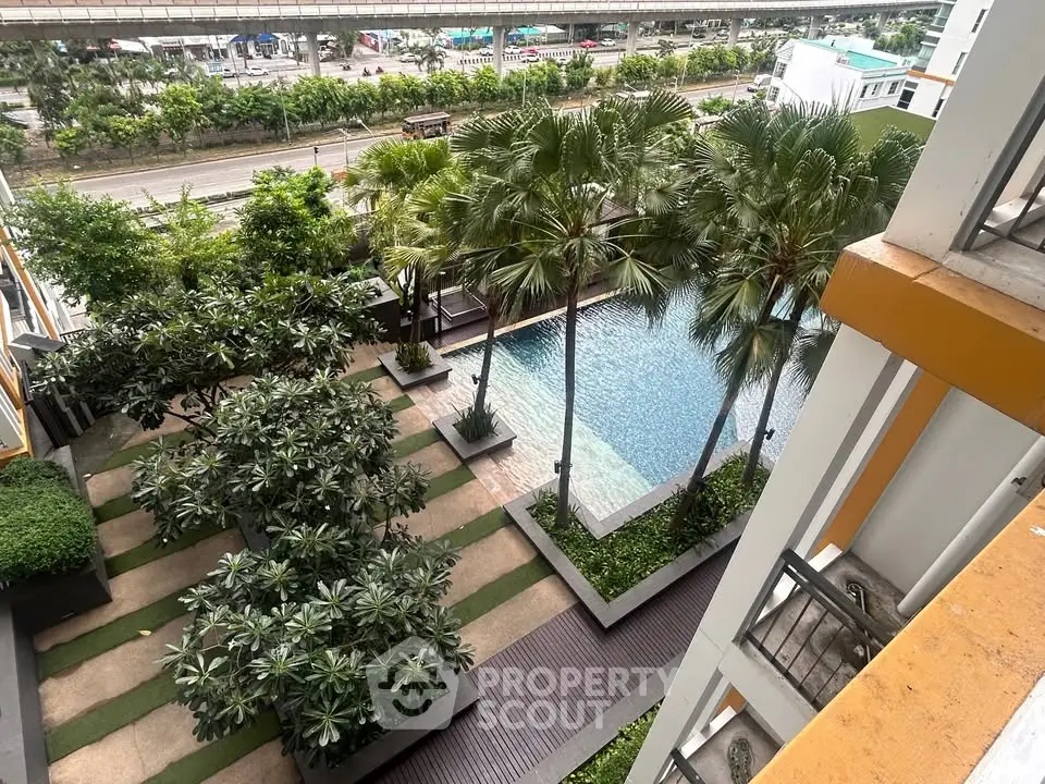 Stunning aerial view of a modern apartment complex with lush greenery and a sparkling pool, perfect for relaxation.