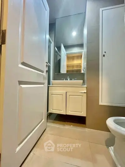 Modern bathroom with sleek vanity and large mirror in contemporary apartment.