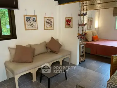 Cozy living area with modern decor and adjacent bedroom in stylish apartment.