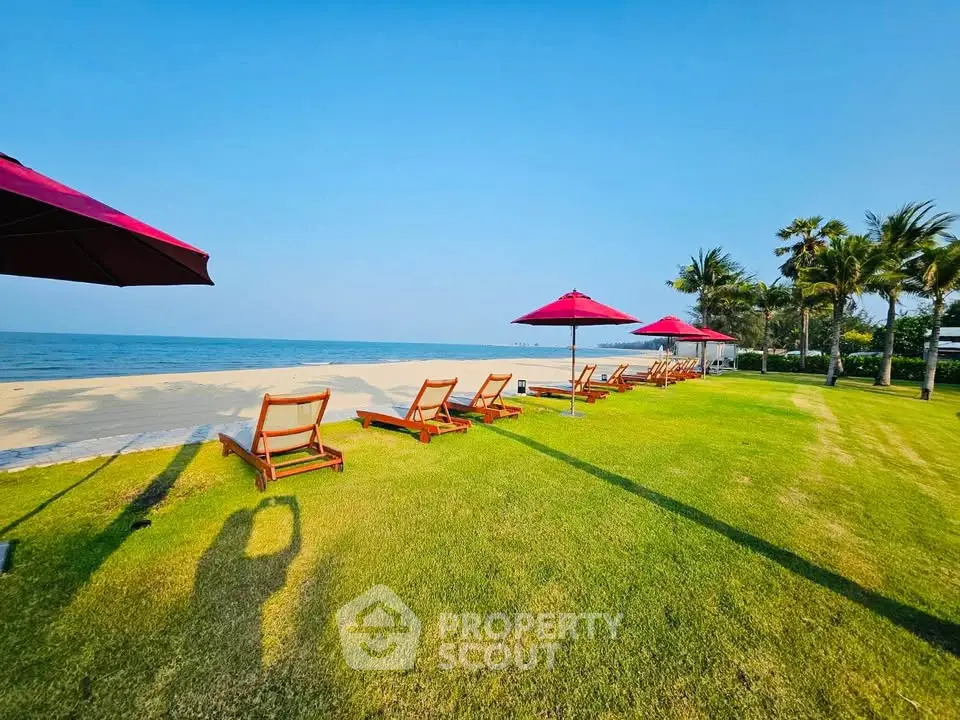 Luxurious beachfront property with pristine sandy shores and lush green lawn, perfect for relaxation.