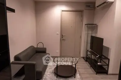 Cozy living room with modern sofa, glass coffee table, and TV setup.