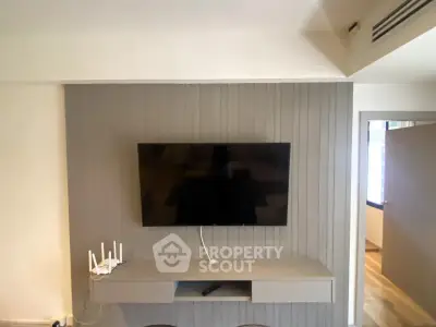 Modern living room with wall-mounted TV and sleek console in stylish apartment.