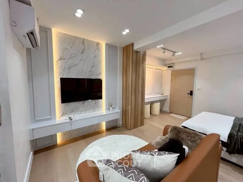 Modern living room with stylish decor and cozy seating area, featuring a mounted TV and elegant lighting.