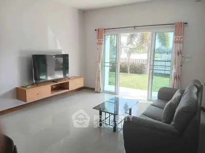 Spacious living room with modern furniture and garden view through sliding glass doors.