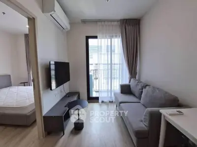 Modern living room with gray sofa, wall-mounted TV, and balcony access in a stylish apartment.