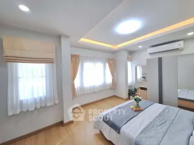 Spacious bedroom with modern decor and natural light, featuring elegant curtains and cozy bedding.