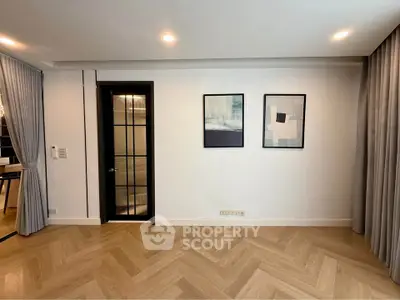 Elegant modern living room with herringbone wood flooring and stylish wall art.