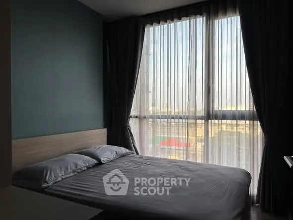 Modern bedroom with large window and city view, featuring sleek design and ample natural light.