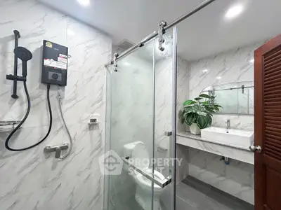 Modern bathroom with glass shower, sleek fixtures, and elegant marble walls.