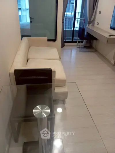 Modern living room with beige sofa and glass table, featuring a sleek design and cozy atmosphere.