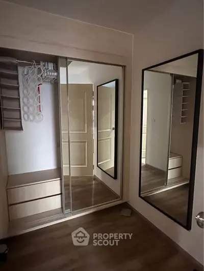 Modern bedroom with mirrored wardrobe and wooden flooring
