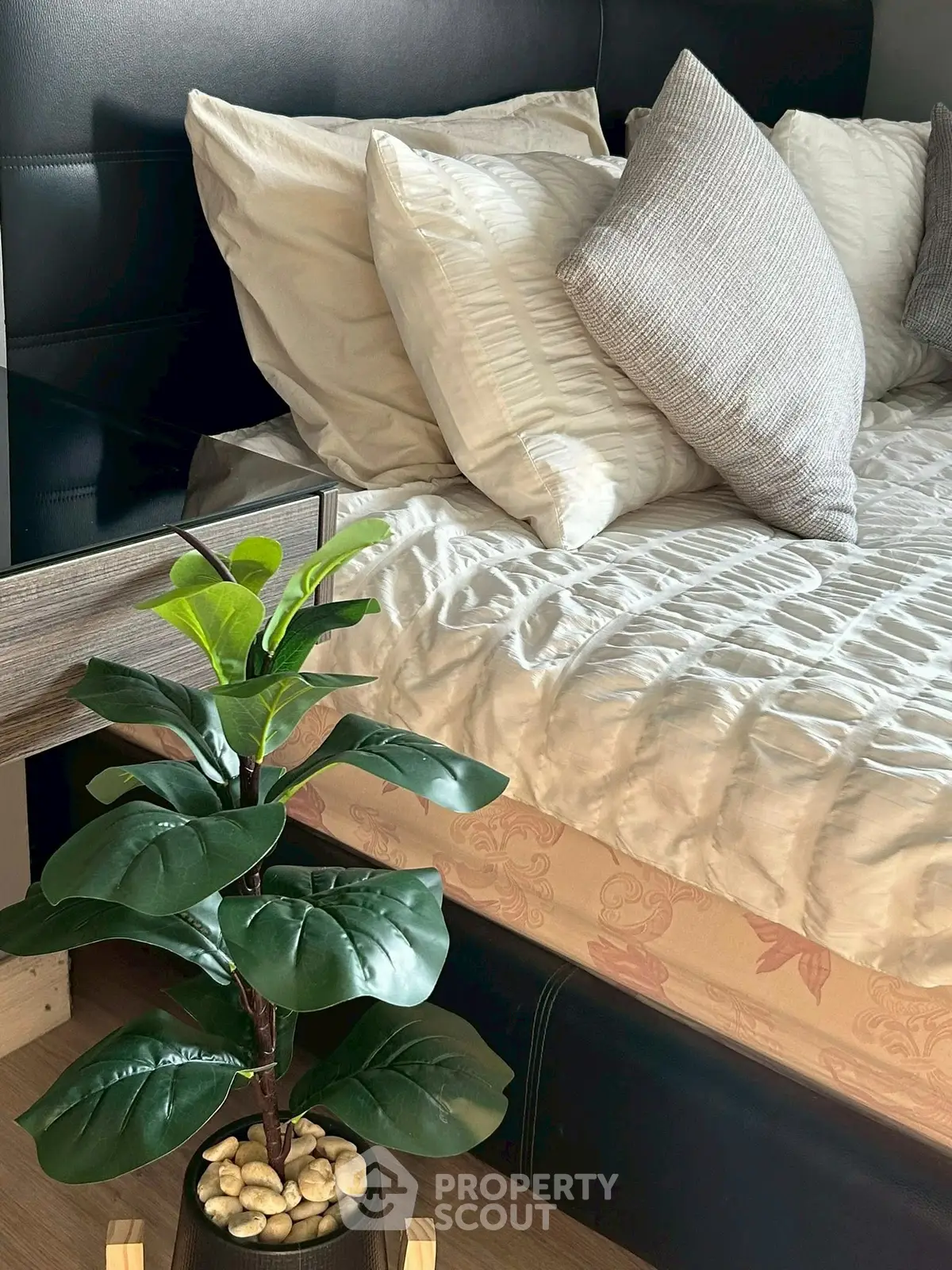 Cozy bedroom with stylish bedding and decorative plant for a serene ambiance.