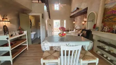 Charming rustic living room with high ceilings and cozy decor, featuring a dining area and unique architectural details.
