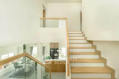 Modern interior with wooden staircase and open kitchen layout, bright and inviting space.