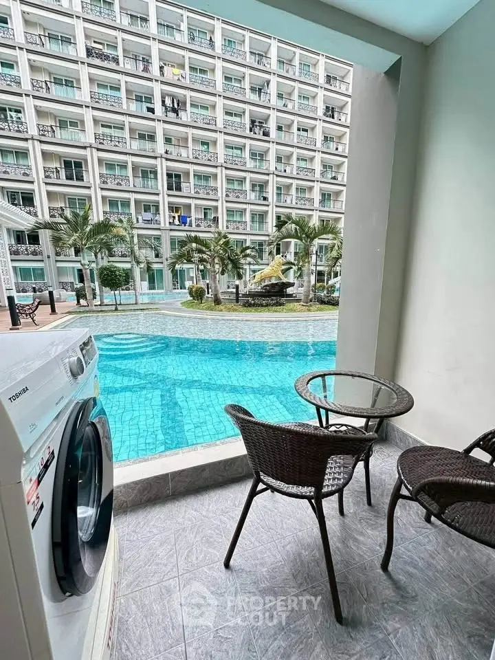 Luxurious poolside view from a modern apartment balcony with washer and outdoor seating.