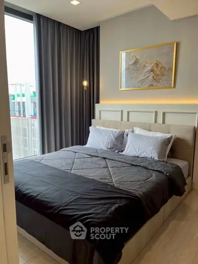 Modern bedroom with large window and stylish decor in urban apartment.