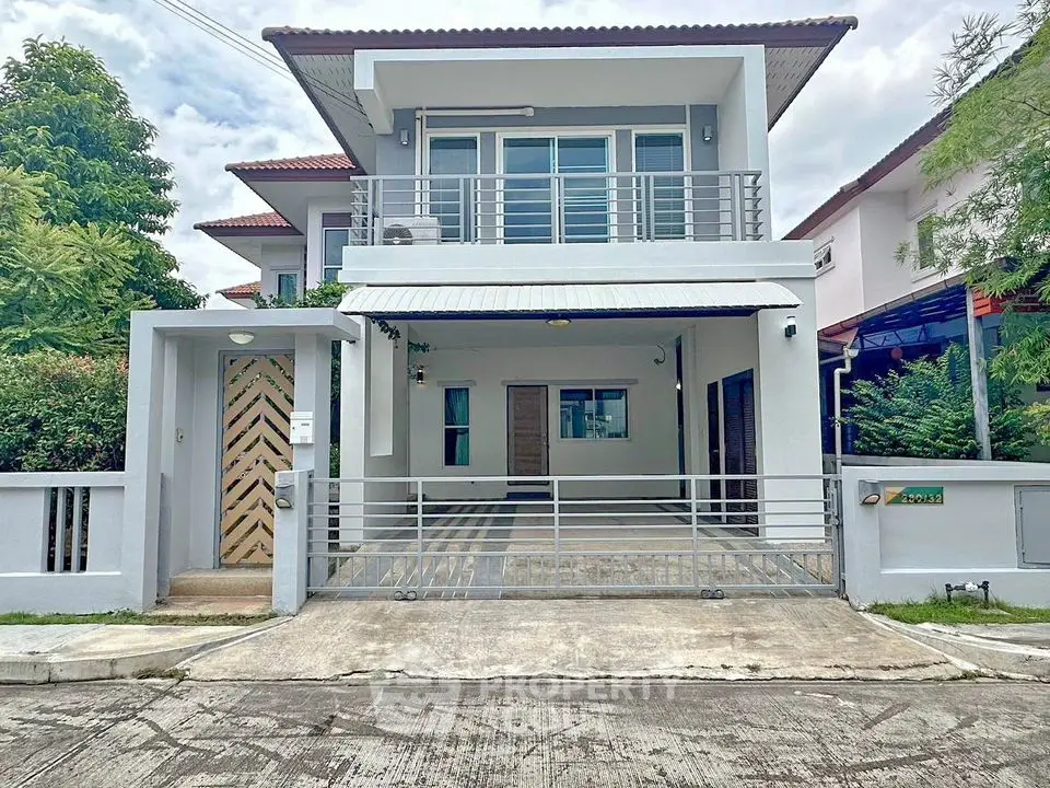 Modern two-story house with gated entrance and driveway in a suburban neighborhood.