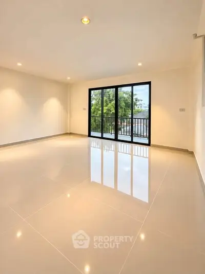 Spacious living room with large windows and glossy tiled floor, offering a serene view.