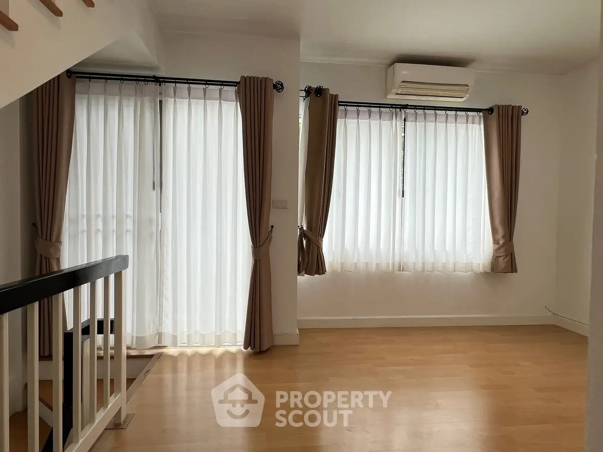 Bright and airy living room with large windows and elegant curtains, featuring a modern air conditioning unit.