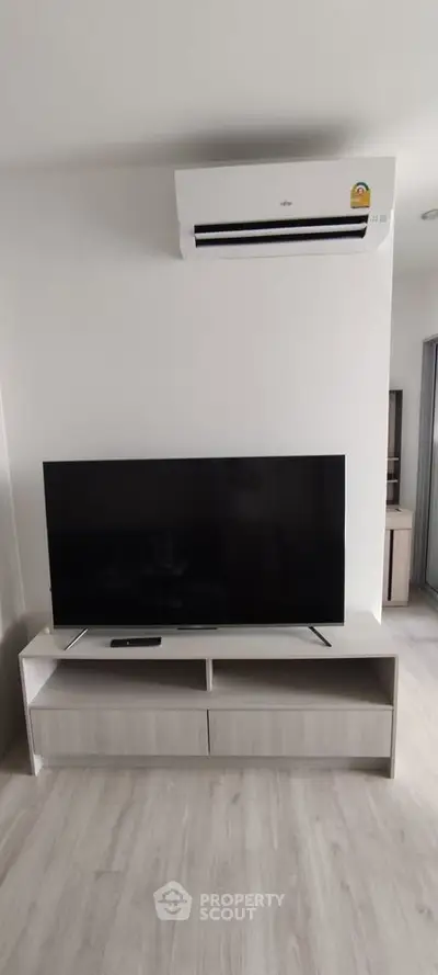 Modern living room with sleek TV setup and air conditioning unit, perfect for comfortable living.