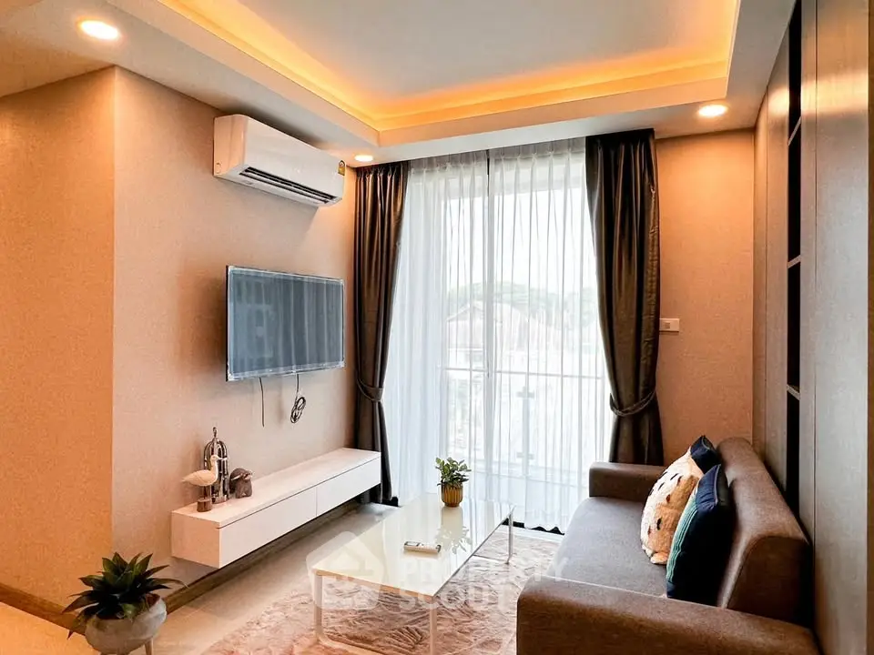 Modern living room with stylish decor, wall-mounted TV, and large window for natural light.