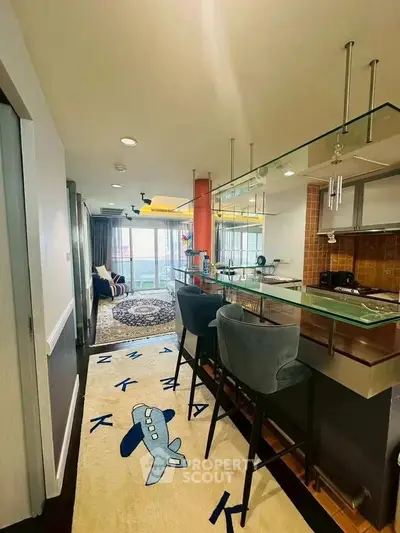 Stylish open-layout kitchen with modern bar seating and cozy living area in a bright apartment.