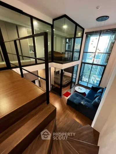 Modern duplex apartment with stylish staircase and cozy living area, featuring floor-to-ceiling windows and city views.