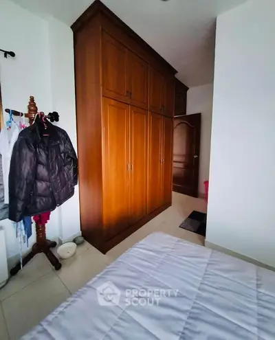 Cozy bedroom with wooden wardrobe and coat rack, perfect for organized living.