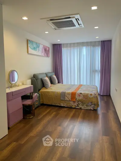 Elegant bedroom with modern decor, featuring a cozy bed, stylish vanity, and floor-to-ceiling windows with purple curtains.