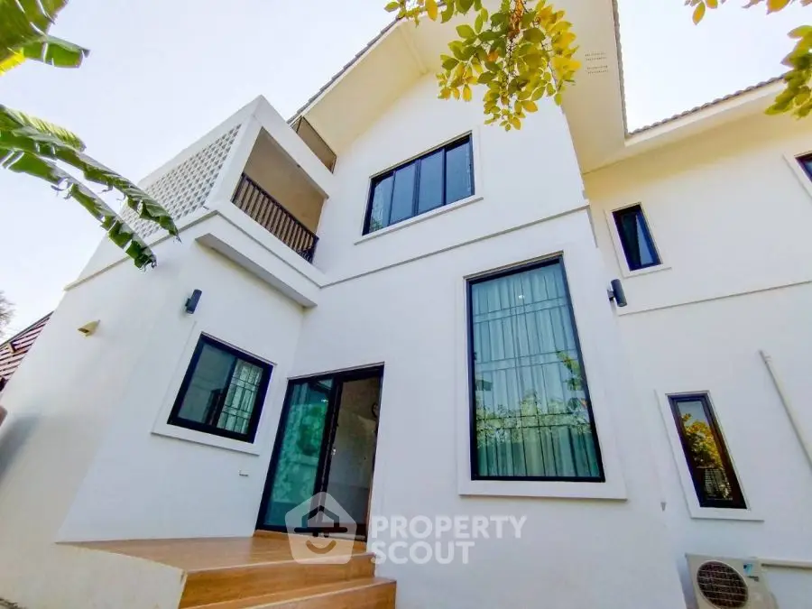 Modern white two-story house with large windows and balcony