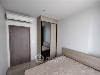 Modern minimalist bedroom with air conditioning and wooden wardrobe, perfect for comfort and style.