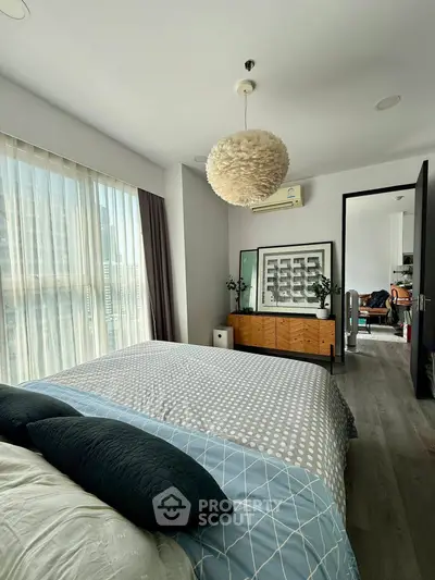 Spacious bedroom with modern decor and large window for natural light