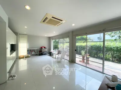 Spacious living room with large windows and garden view, perfect for relaxation and entertaining.