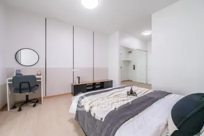 Modern bedroom with stylish decor and workspace, featuring a cozy bed and sleek design.