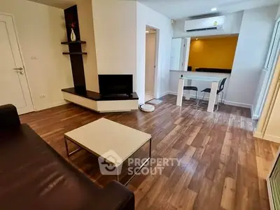 Modern living room with wooden flooring and open kitchen layout in a stylish apartment.
