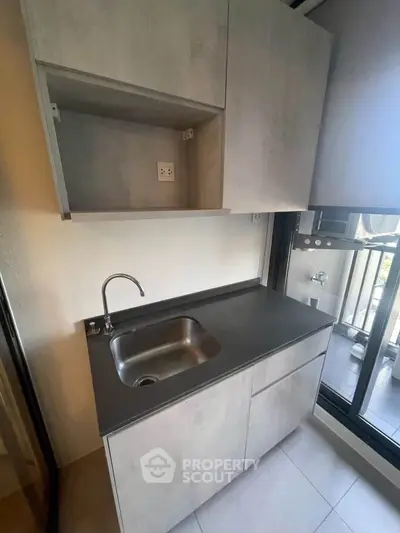 Modern compact kitchen with sleek cabinetry and balcony access, perfect for urban living.