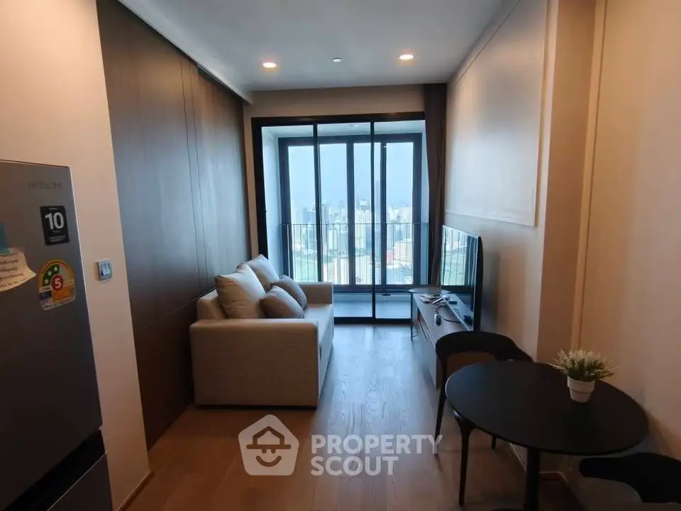 Modern living room with city view and balcony access in high-rise apartment.