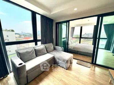 Modern living room with large windows and cozy sofa, adjacent to a bright bedroom with city view.