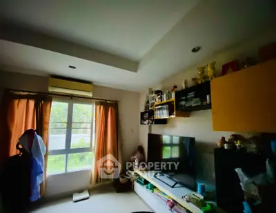 Cozy living room with large window and modern entertainment setup.