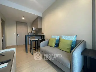 Modern living room with cozy sofa and compact kitchen in open layout apartment.